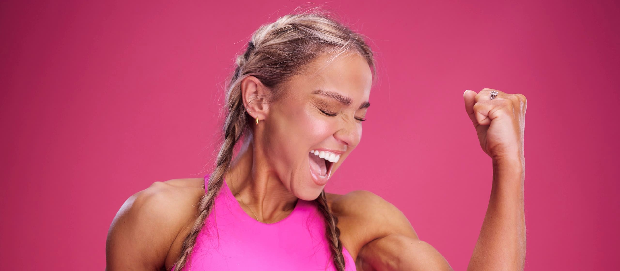 Caroline Girvan, braids and a raised fist, mid-laugh — FUEL Program 2026 shoot.